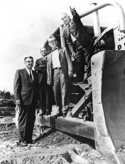 Group of men standing on construction equipment at TCC campus in 1965. Black and white photo.